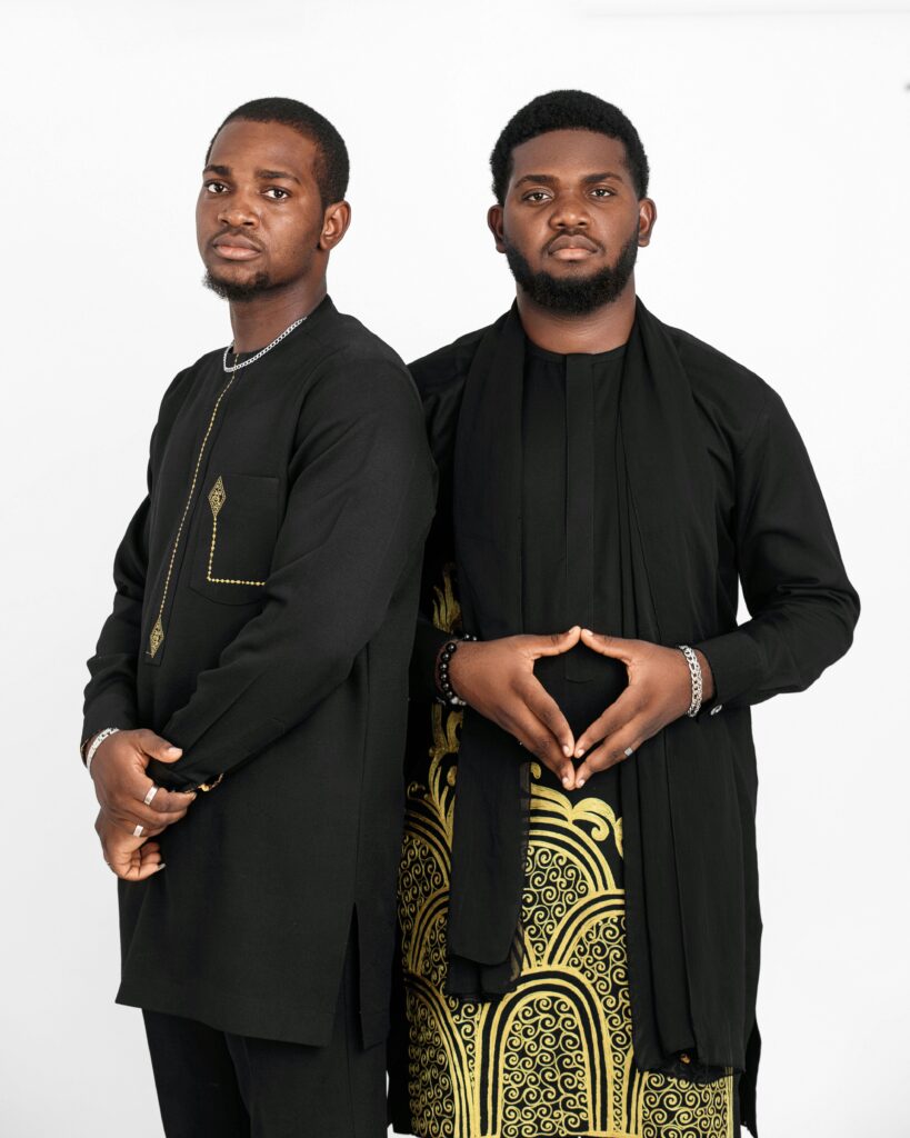 Two men in traditional African attire posing elegantly against a plain white background.